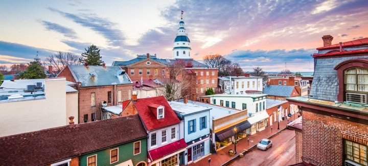Aerial view of a historic town with colorful buildings and a domed government building at sunset.