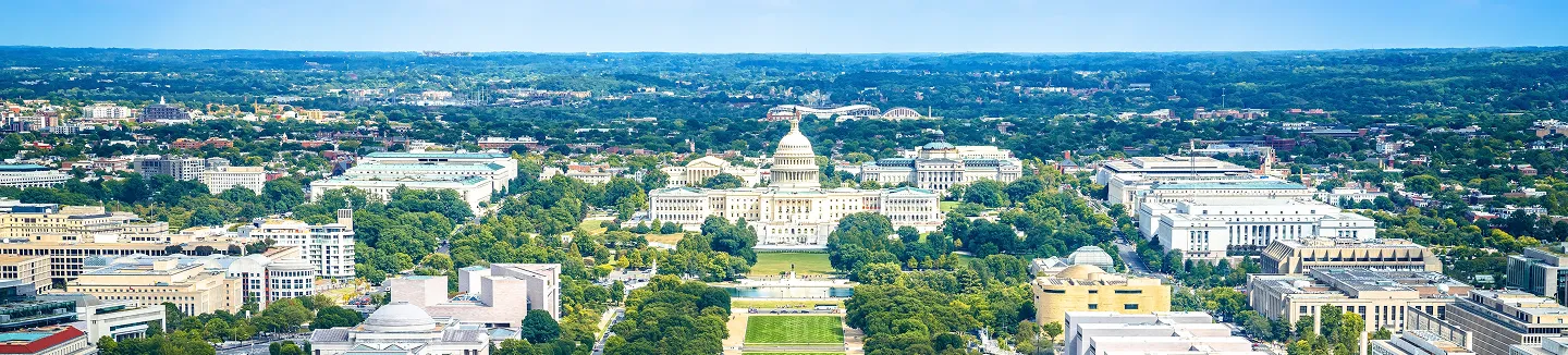 Aerial view of the United States Capitol building surrounded by greenery and cityscape in Washington, D.C.